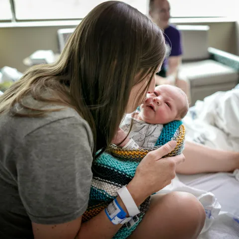 New mother kissing and holding her newborn baby.