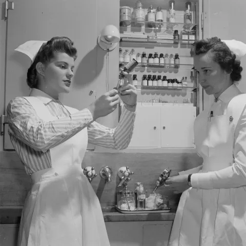 Two nurses preparing a vaccine shot.