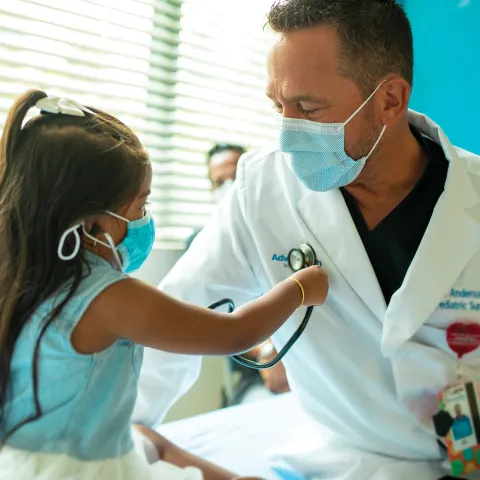 Physician playing with little girl patient