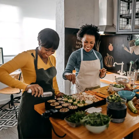 Three women preparing food in a kitchen.