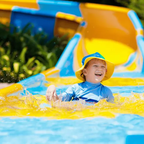 A child having fun sliding on a water slide.