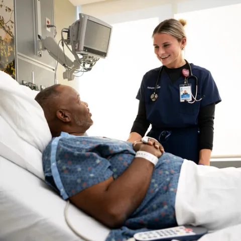 Nurse comforting patient in patient bed,