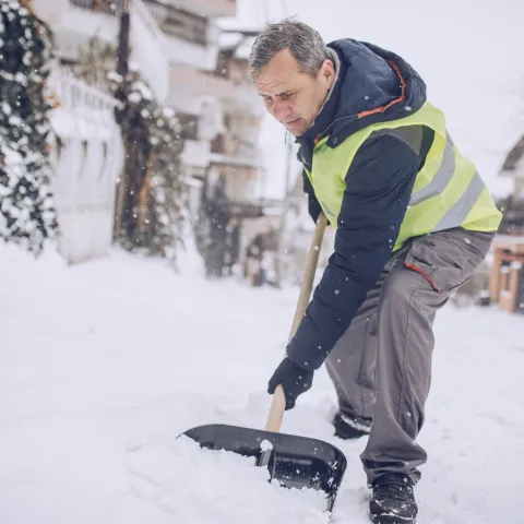 An older man shoveling snow.