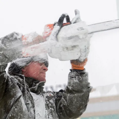 A man using a chainsaw to cut ice.