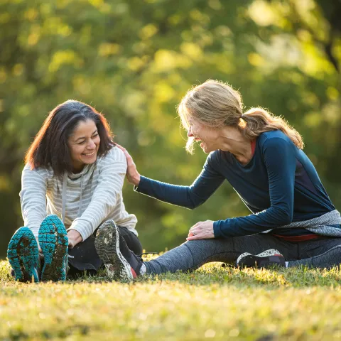 Two friends stretching in the in park. 
