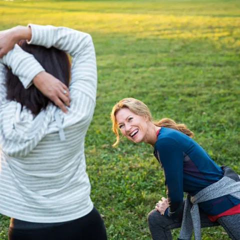 Two friends stretching in the in park during a sunny morning. 