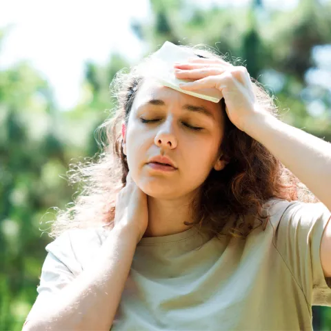 A woman wiping sweat from her brow while walking outdoors.