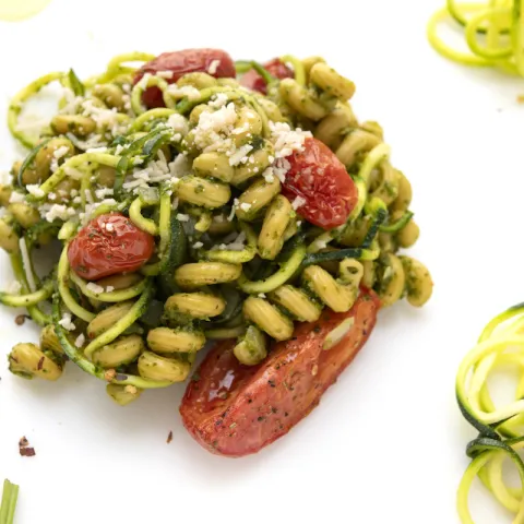 Mound of zucchini spiral pasta on white surface