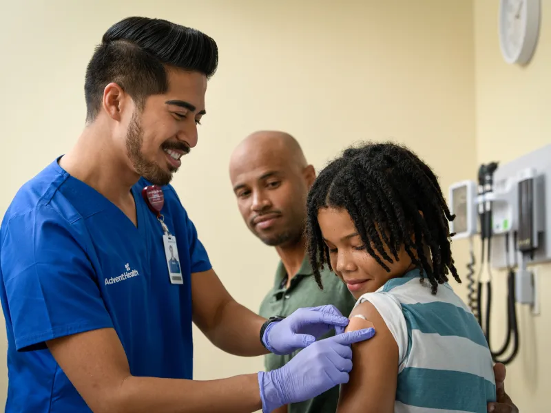 A Provider Puts a Bandage on a Child's Injection Site as They Both Smile.
