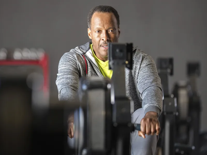An older African American man works out on a rowing machine at the gym.