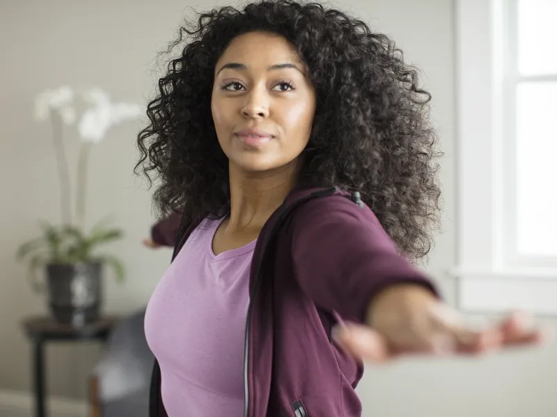 A young woman practices yoga in her home