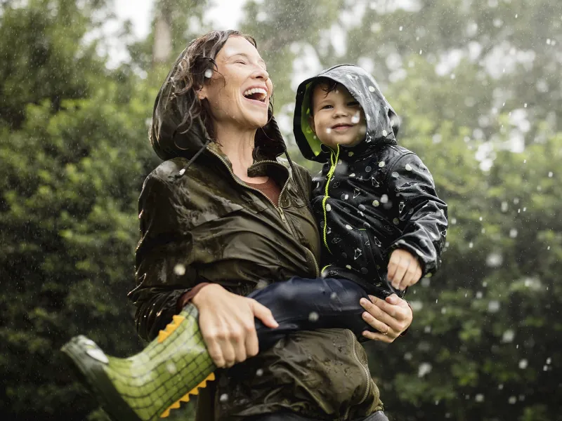 A mother and her young son play in the rain.