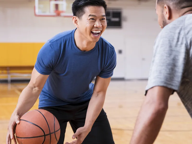 Two men play basketball together at the gym.