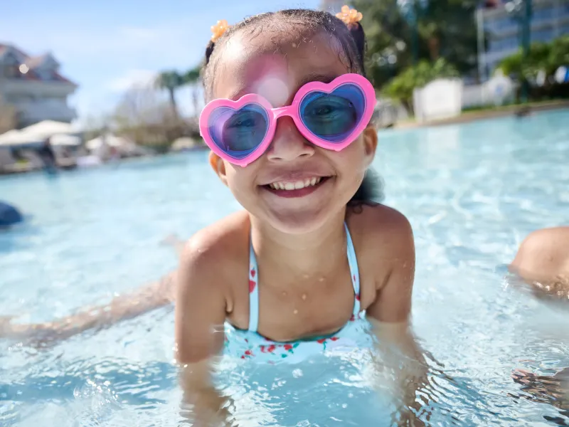 A Little Girl Swims in a Resort Pool Wearing Heart Shaped Goggles