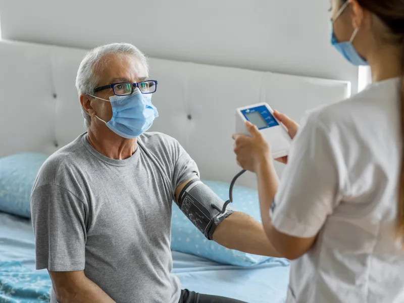 A home care nurse takes a patient's blood pressure.