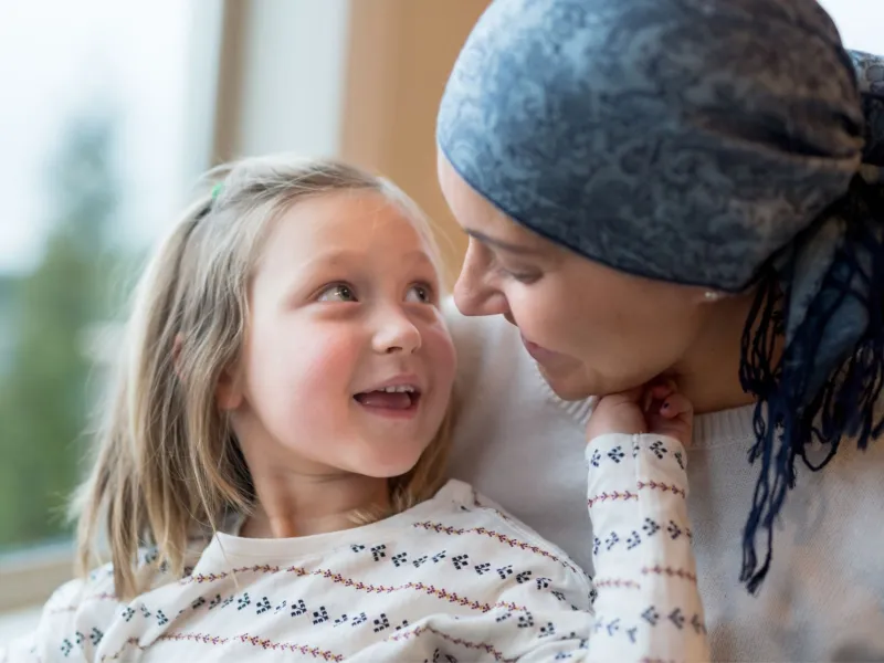 A Small Child Smiles and Touches Her Mother's Face While Sitting in a Window.