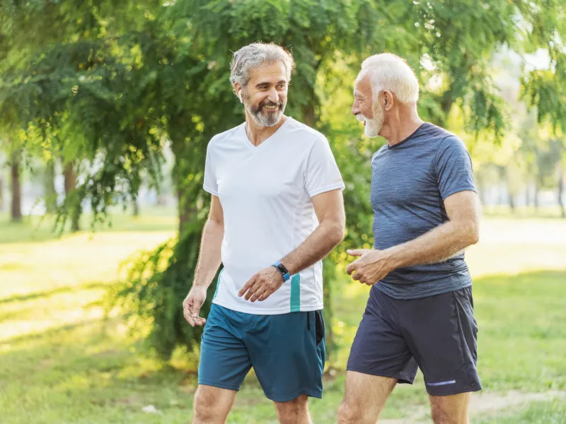 Two Senior Men Walk Through a Park While on a Jog
