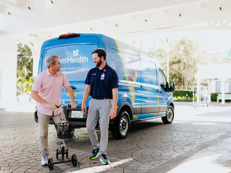 A Patient on a Scooter Smiles with an AdventHealth Employee at a Walt Disney World Resort Hotel