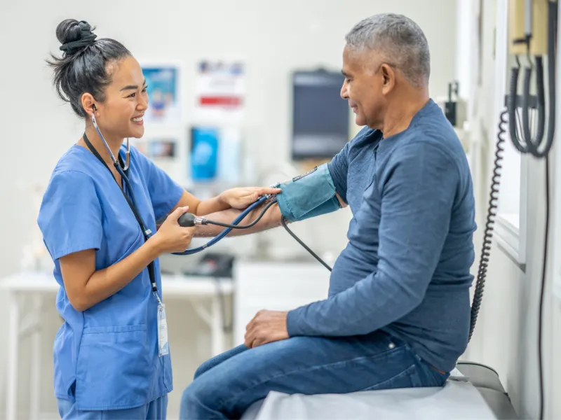 A Nurse Smiles as she Takes a Patient's Blood Pressure Readings.