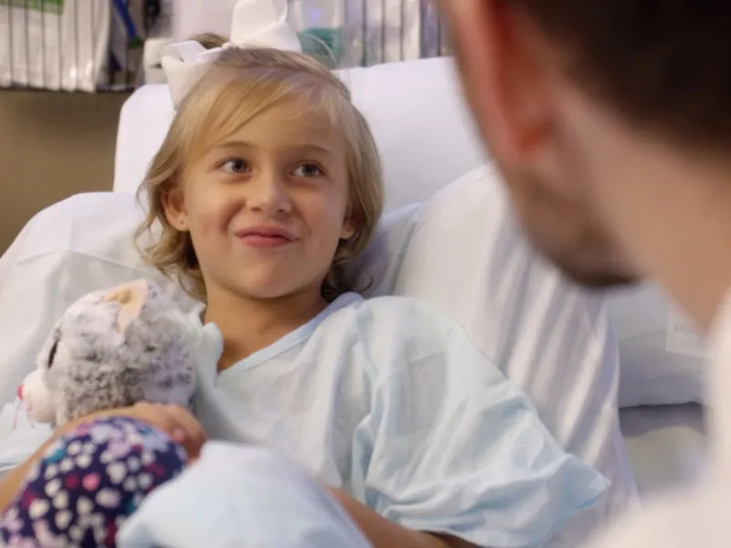 Charlotte sits with her doctor in her hospital room.
