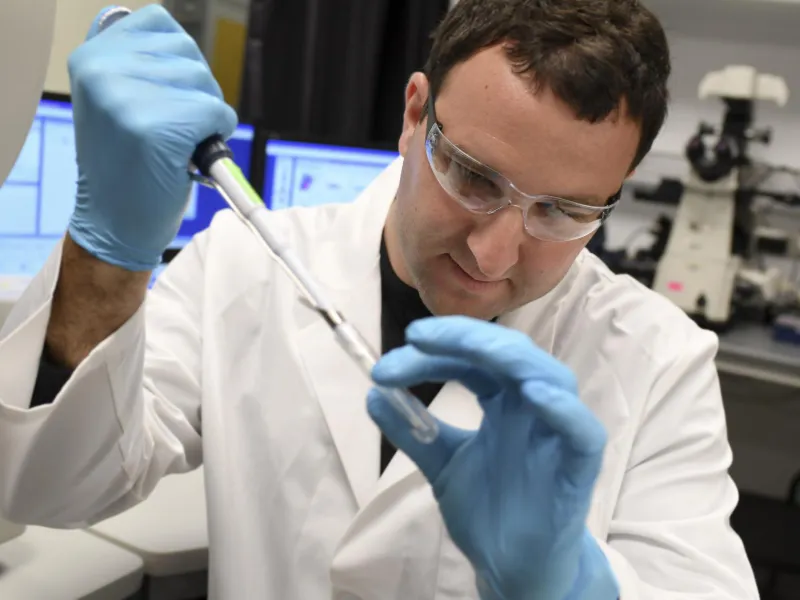 A male researcher examines a test tube in the hospital lab.