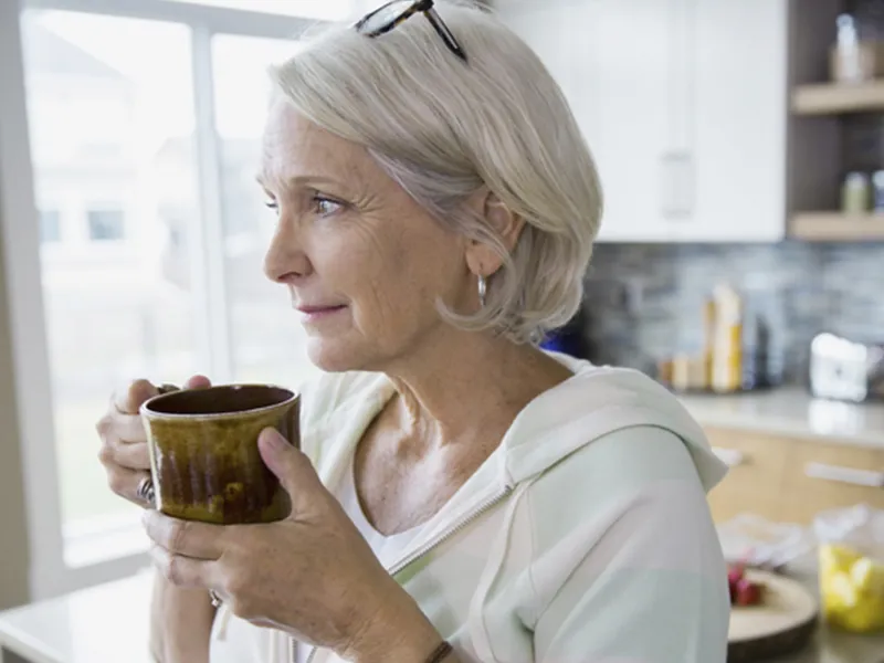 An adult Caucasian woman sips coffee from a mug.