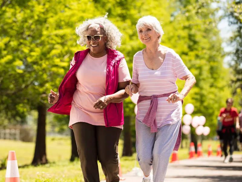 Two elderly women walking in the park.