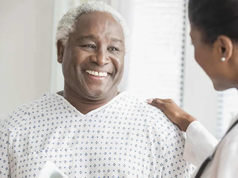An older African American man receives consolation from a female physician.