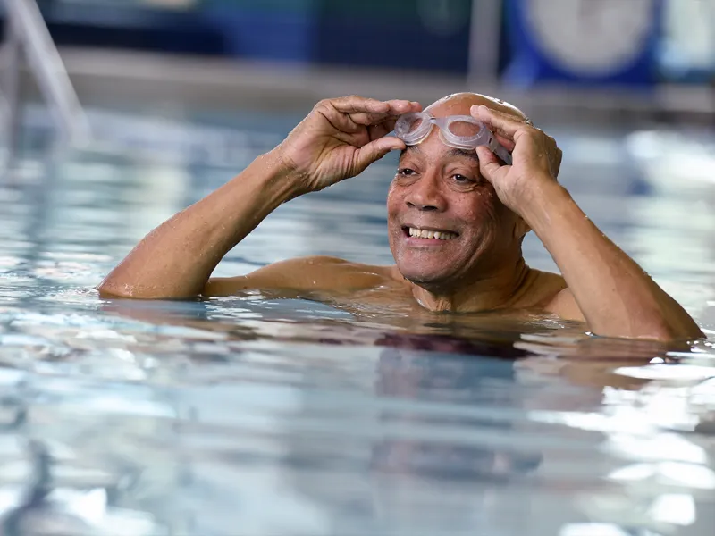 An older man puts on his goggles in an indoor exercise pool