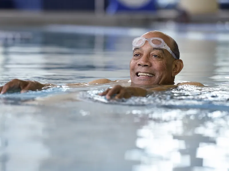 An African American man swims in an indoor pool for exercise