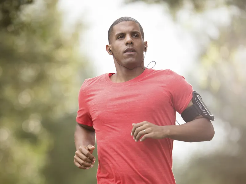 A young man listens to headphones while jogging outdoors