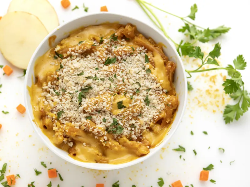 Bowl of mac and cheese with potato and parsley garnish