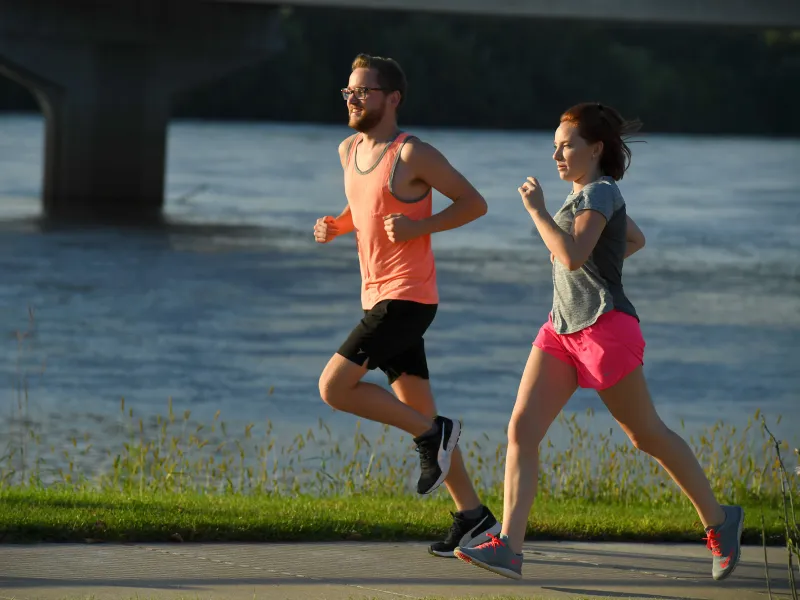 A young couple taking a morning run around a lake.