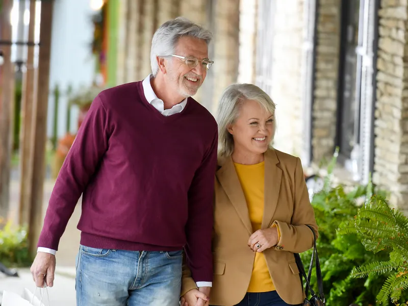 Elderly couple walking down a sidewalk window shopping.