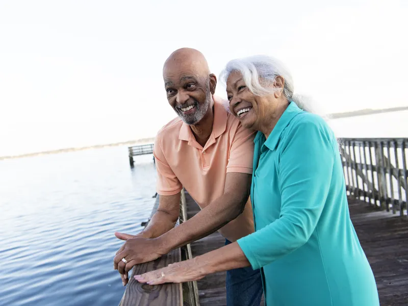 Older couple leaning on the pier looking at the lake