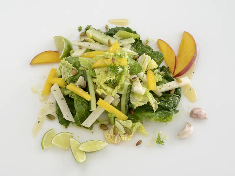 Mound of jicama, cabbage, and mango salad on white surface.