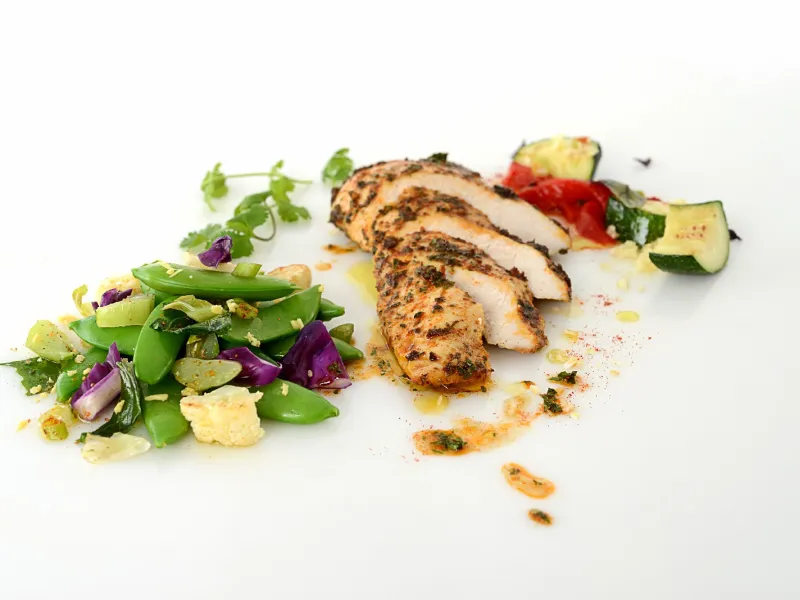 four slices of roasted chicken served with roasted vegetables