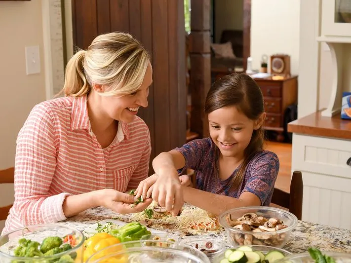 A mom teaches her daughter a recipe in the kitchen