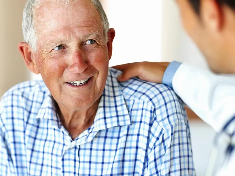 Doctor with his hand on an elderly man's shoulder