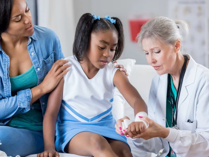 Doctor checking the arm of a young cheerleader.