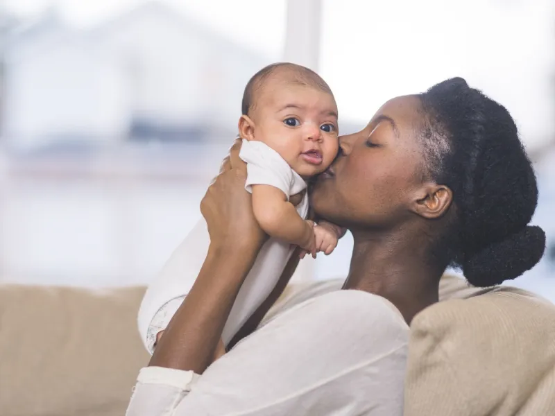 Young mother holding and kissing her baby.