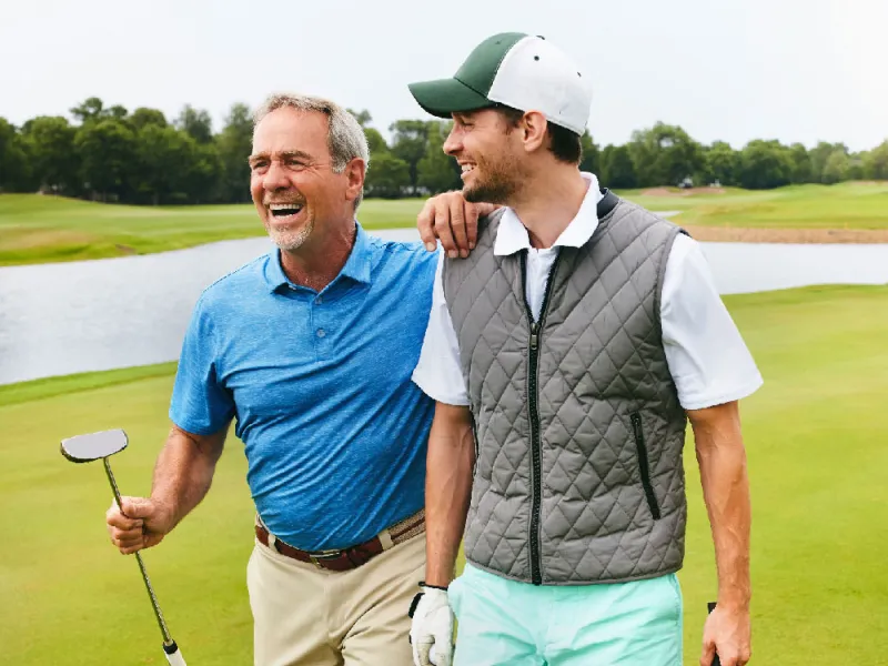 Two grown men walking away from a golf hole