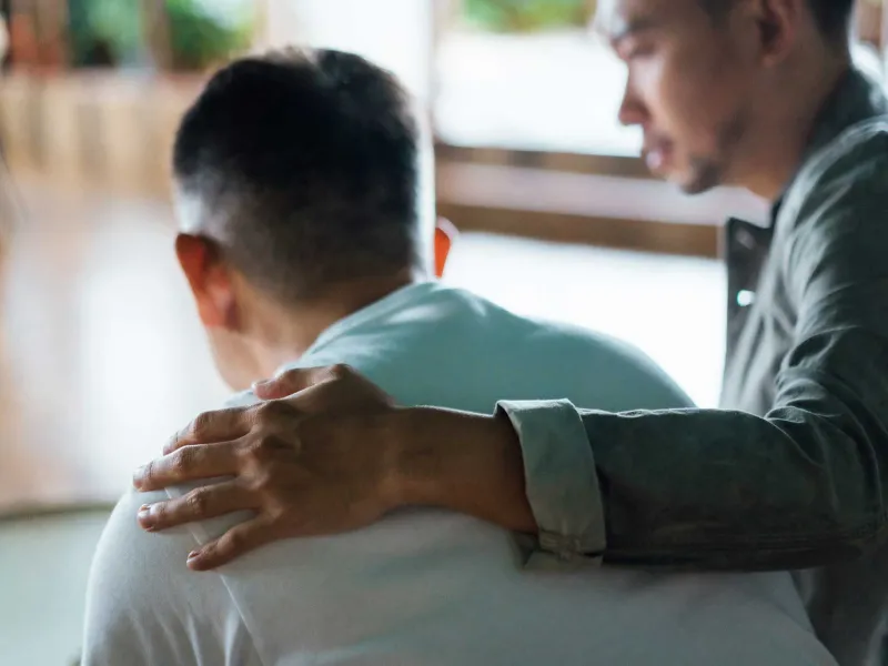 A young man having his arm around a mature man
