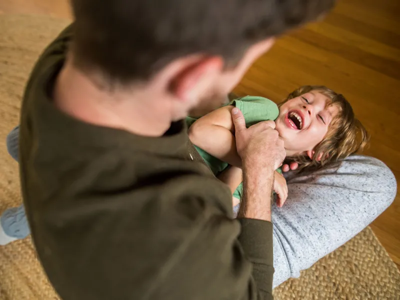 A dad is tickling his son.