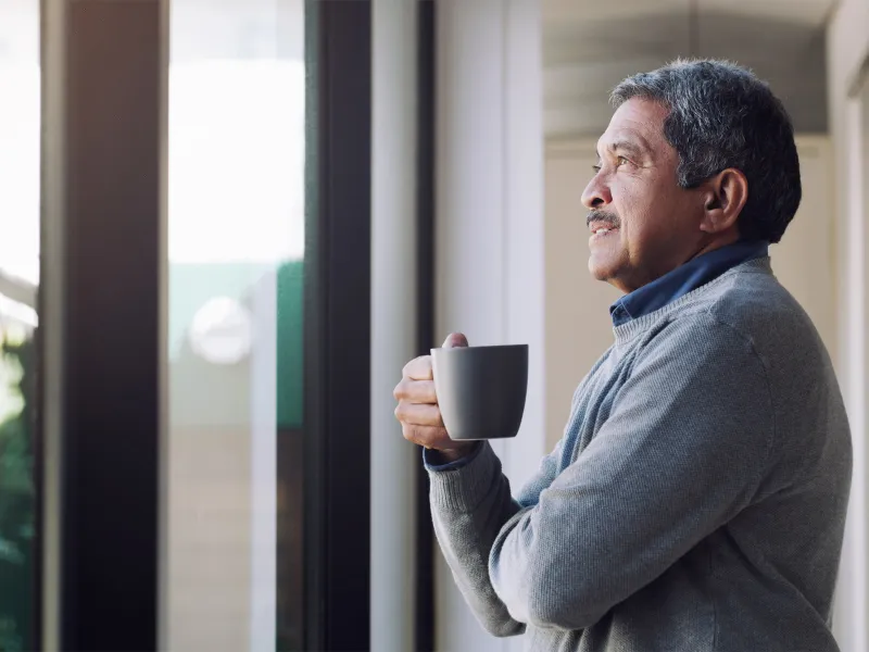 Older man enjoying a cup of coffee while looking out the window