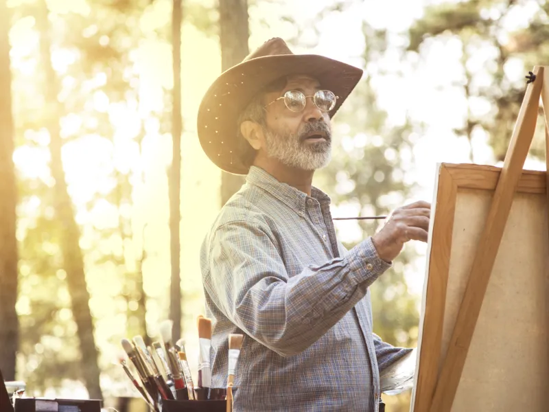 Older man painting outdoors.