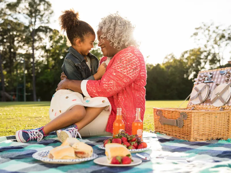 A grandmother having a picnic with her grand-daughter at the park.