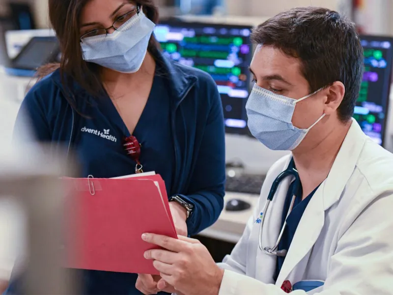 An Adventhealth physician and nurse going through a patient's file.