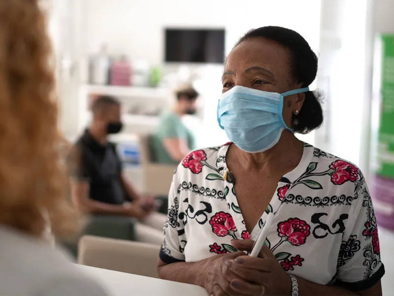 Older woman at a doctor's office wearing a mask.