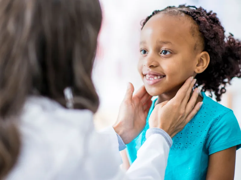A girl has her throat checked at a doctor's appointment.